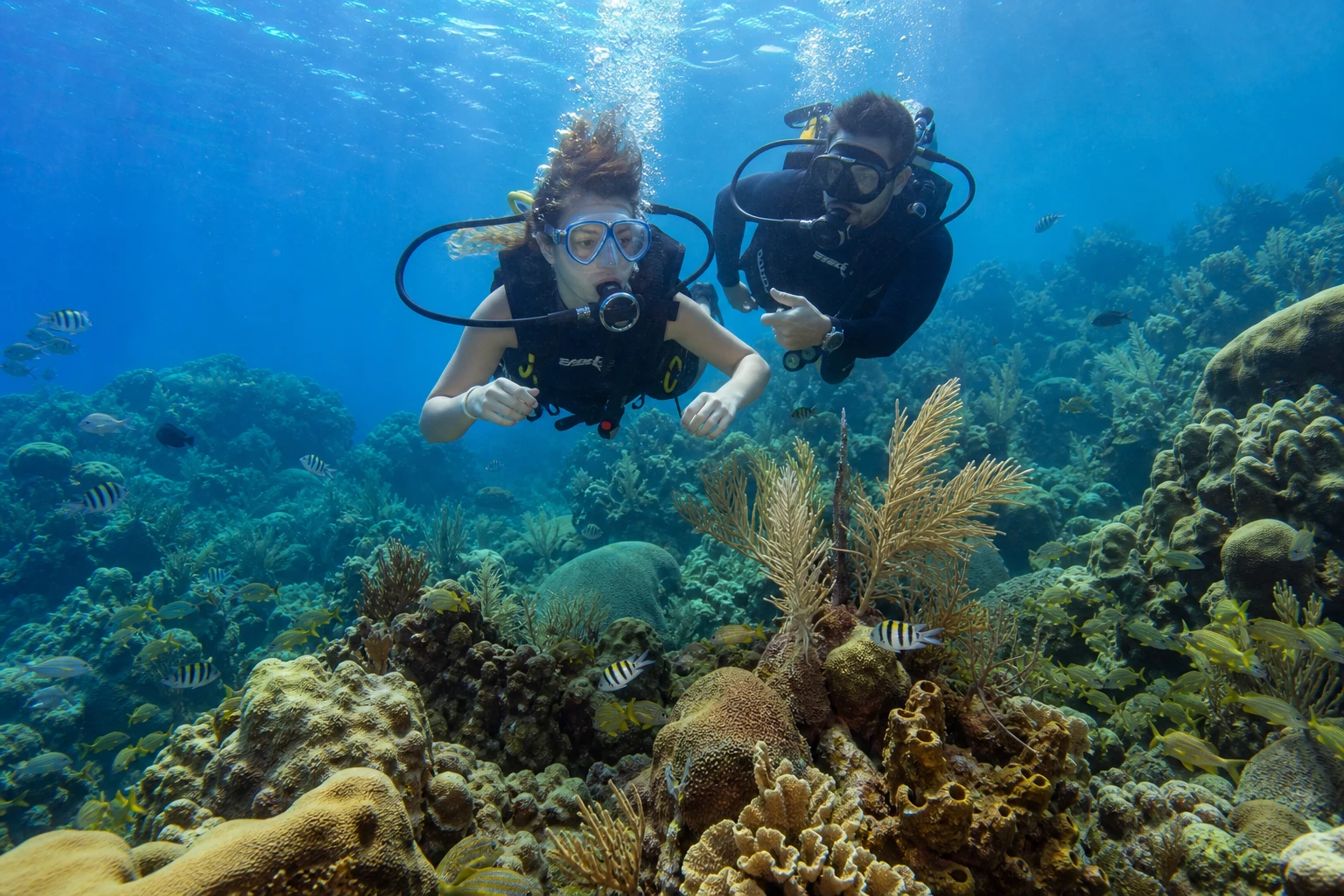 Beginner scuba diver and instructor above a Belize coral reef