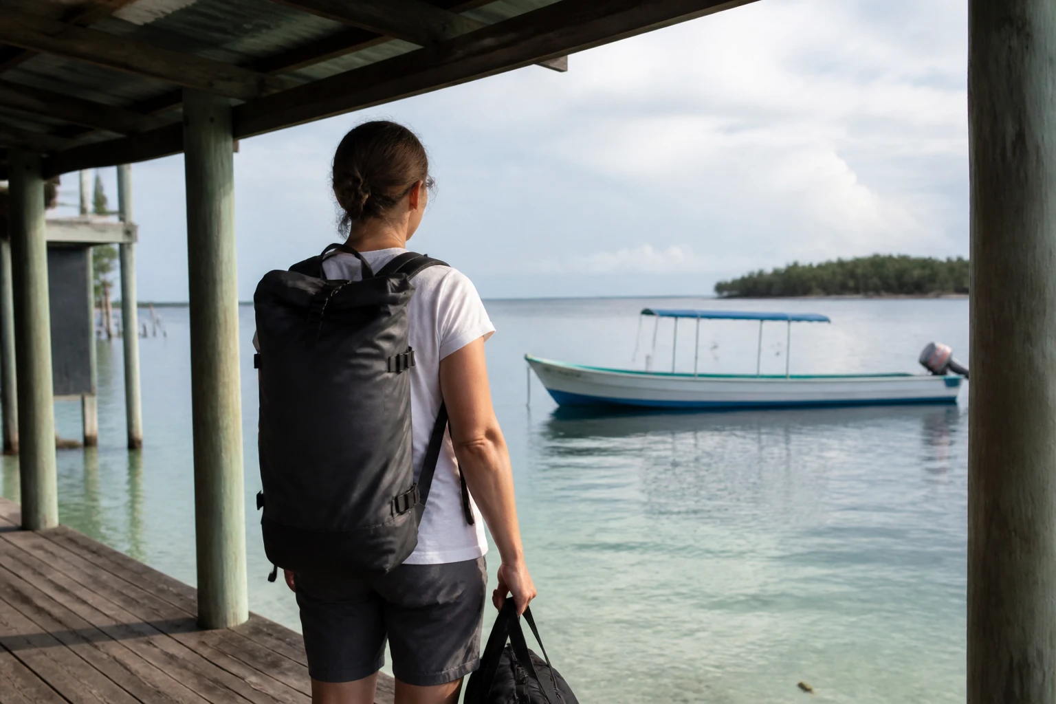 Traveler waiting at a Belize dock with a waterproof day bag