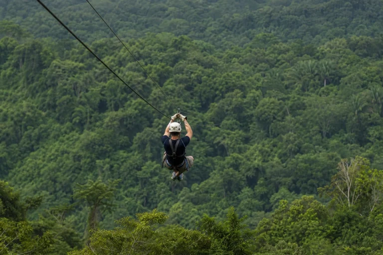 Zipline rider crossing above rainforest canopy in Belize