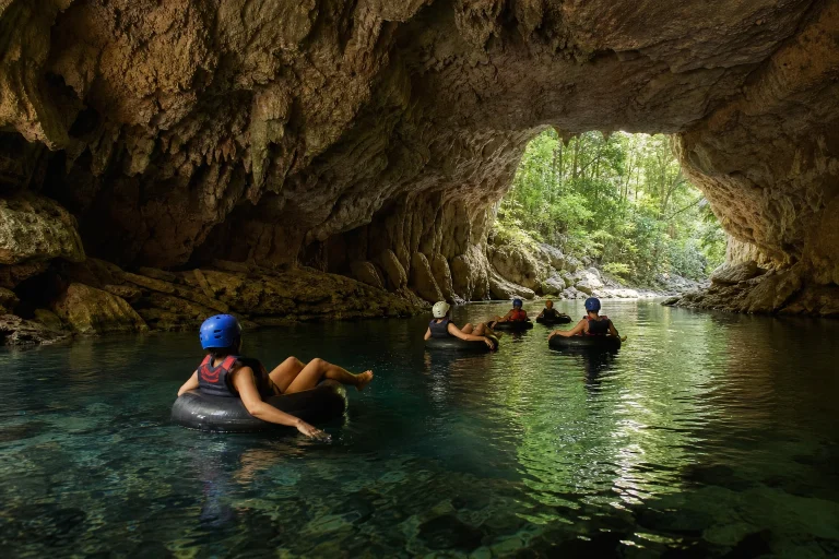 Travelers floating through a limestone cave on a Belize tubing excursion
