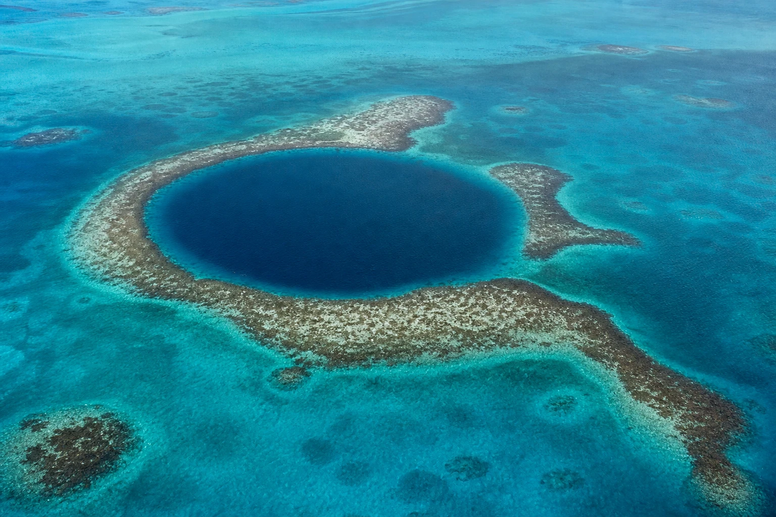 Aerial view of Belize’s Great Blue Hole surrounded by turquoise reef water